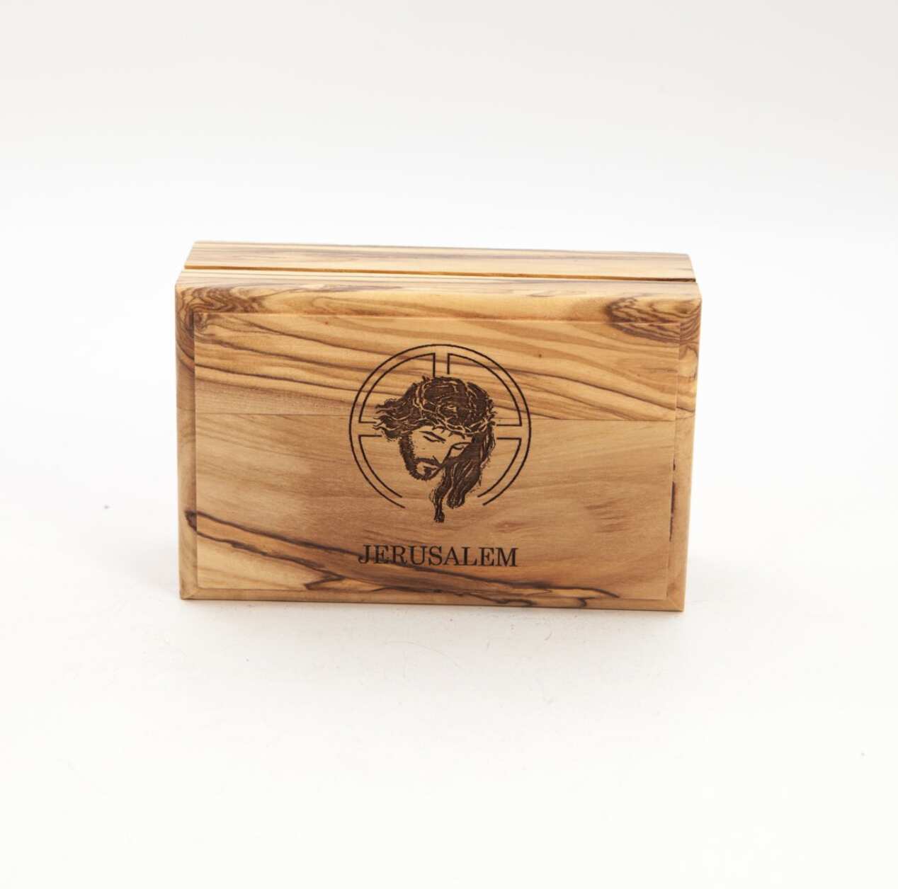 A rectangular olive wood Jesus Christ engraved wooden box with a lid, on a white background. The box has a soft red felt lining and the word 'Jerusalem' carved below the image of Christ.