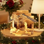 Wooden nativity scene with Mary, Joseph, and baby Jesus on a table with Christmas decorations.