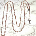 A 15 Decade Wall Rosary with pink crystal beads and a metal chain, placed on a marble surface.