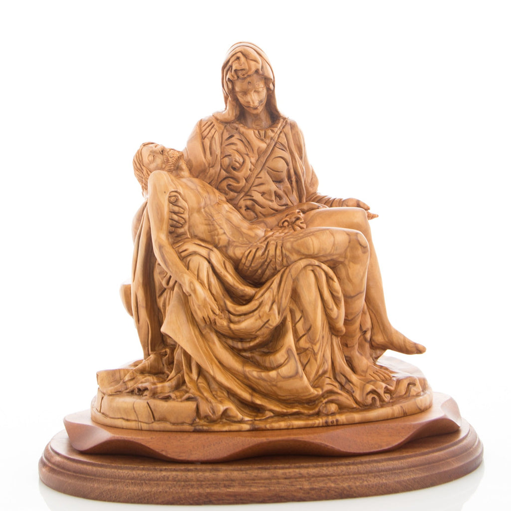 A wooden carving statue of the Pieta, featuring the Virgin Mary sitting next to the lifeless body of Jesus, on a wooden base.