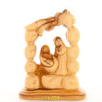 A wooden carving depicting the nativity scene with the Holy Family, including Joseph, Mary, and baby Jesus, surrounded by a star and an arch.