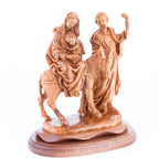A wooden statue depicting the Holy Family on a donkey, with Joseph holding the reins, Mary sitting behind, and baby Jesus on the donkey's back.