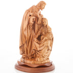 An olive wood carved sculpture of the Holy Family holding a lamp, with Saint Joseph holding a lantern and Jesus being cradled by Mary.