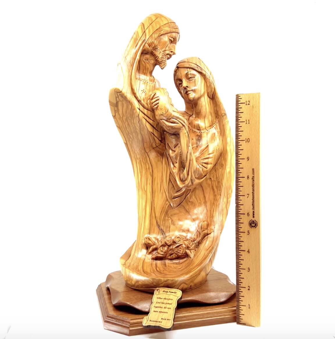 A wooden sculpture of the Holy Family Nativity, carved in olive wood, with measurements taken for scale.